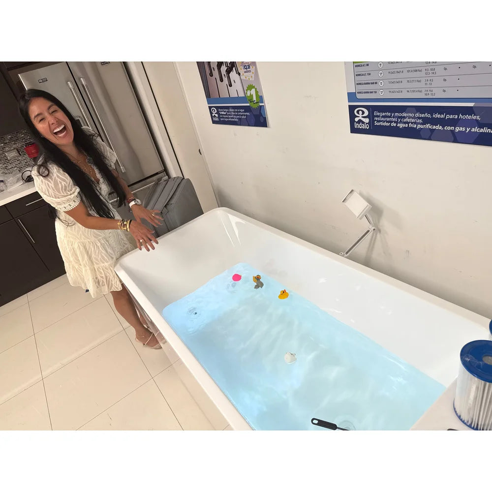Laughing woman resting on the rim of the water-filled AMBOHR All-in Ice Bath Tubs unit with ducks floating