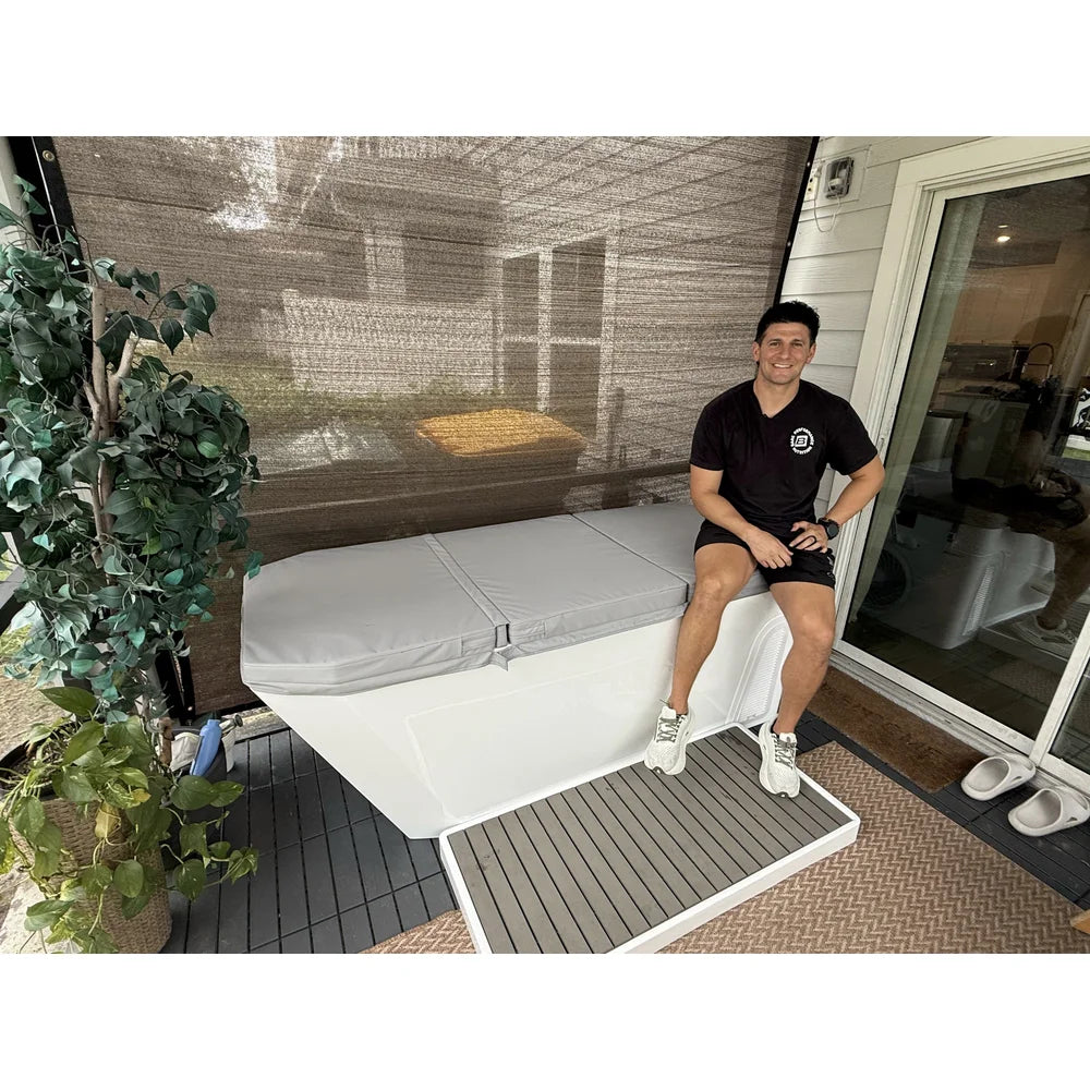 Owner seated on the closed thermal cover of the AMBOHR All-in Ice Bath System on a screened patio