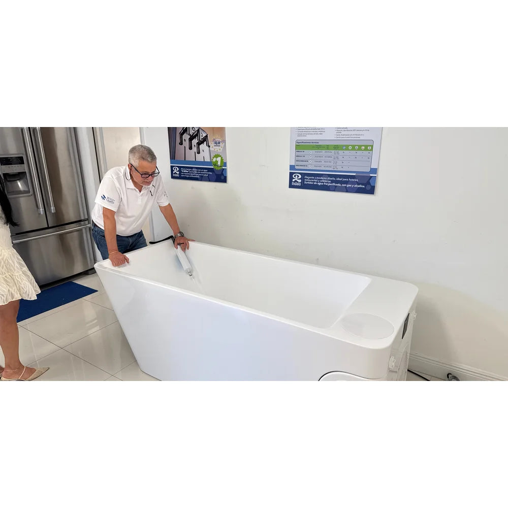 Showroom staff member leaning over the empty AMBOHR All-in Cold Plunge Spa while holding the filter hose