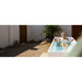 Wide courtyard banner of a woman reclining in the AMBOHR All-in Ice Bath Tubs unit beside a palm tree