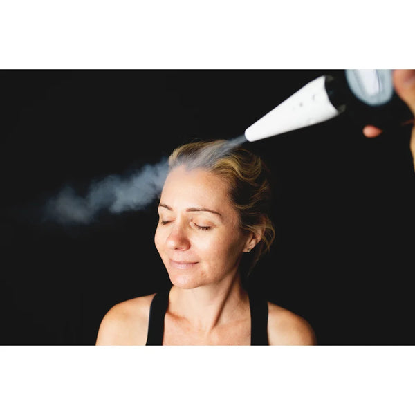 Cone nozzle spraying CO2 vapor across a woman's forehead during a facial with the America Cryo SubZero fat reduction machine
