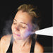 Cold plume from the America Cryo SubZero cryotherapy unit directed at a woman's cheek during a cryo facial