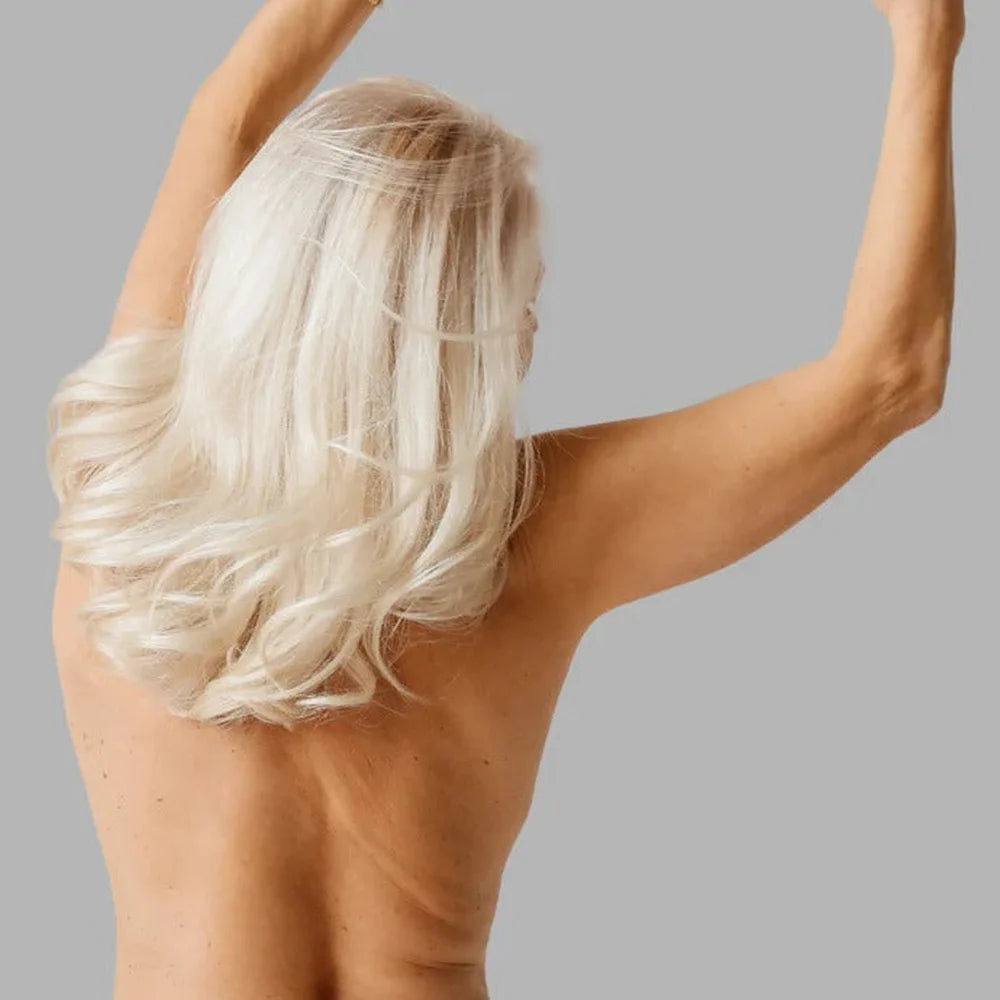 Woman seen from behind with a raised arm and smooth firm back skin, results tied to the Galaxy Zero Atlas Red Light Therapy Device