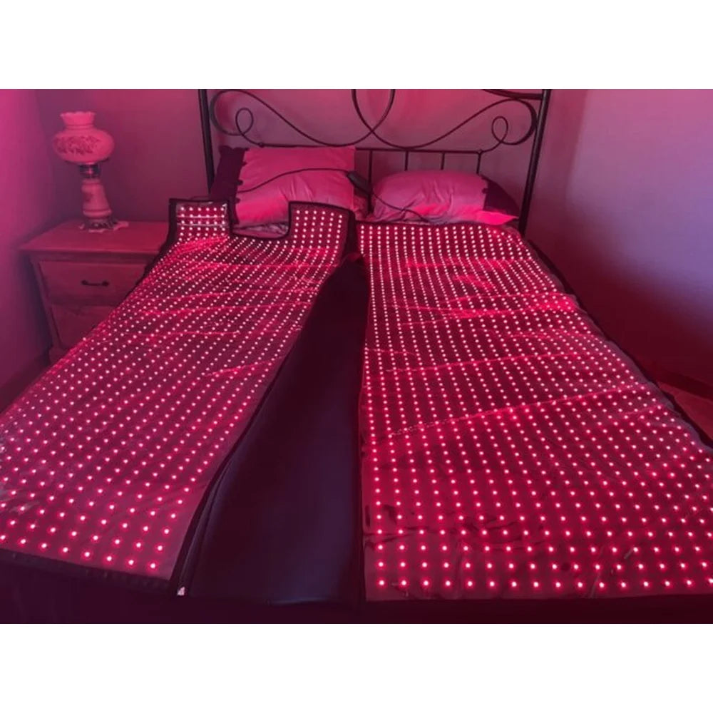Open wrap spread across a bed with both panels lit, shown as a Kore KoreKapsule Near Infrared Light Therapy Device at home