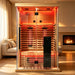 Blisspod Vantaa RED Deluxe Sauna set up in a living room beside a fireplace with heaters glowing behind glass doors