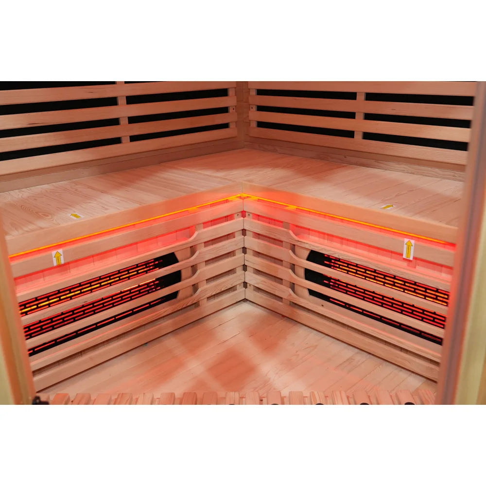 Two glowing full spectrum heaters under the corner bench and red chromotherapy strip in the Blisspod Vienna RED Red Light Therapy Sauna