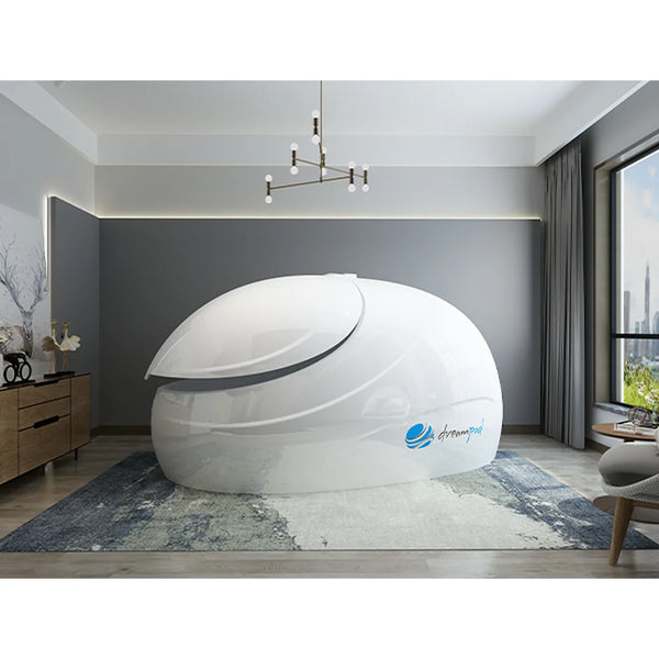 Angled front view of the white Dreampod Sport Flotation Tank with closed lid and blue shell logo in a grey room