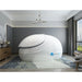 Angled front view of the white Dreampod Sport Flotation Tank with closed lid and blue shell logo in a grey room