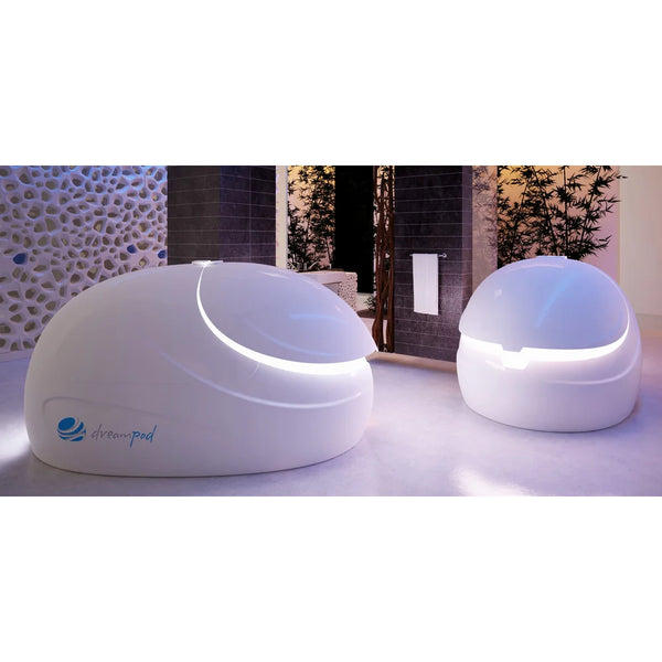 Pair of Dreampod Sport Float Tank units with glowing rim lighting arranged in a dark stone-walled spa room