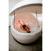Woman floating on her back inside a Dreampod V2 Float Tank with the lid open and pink chakra lighting