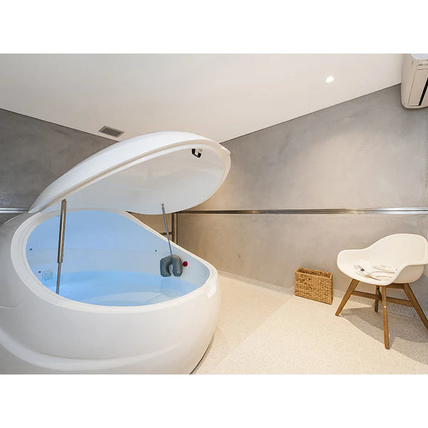 Open white Dreampod V2 with pale blue salt water, hanging neck pillow and gas springs in a grey float room