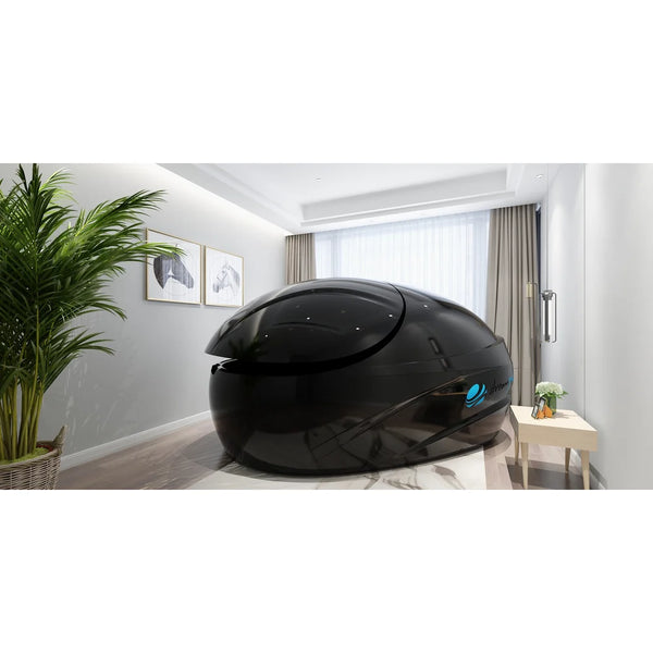Gloss black pod with blue side logo and closed lid in a bright room with a palm, the Dreampod Vmax in black finish