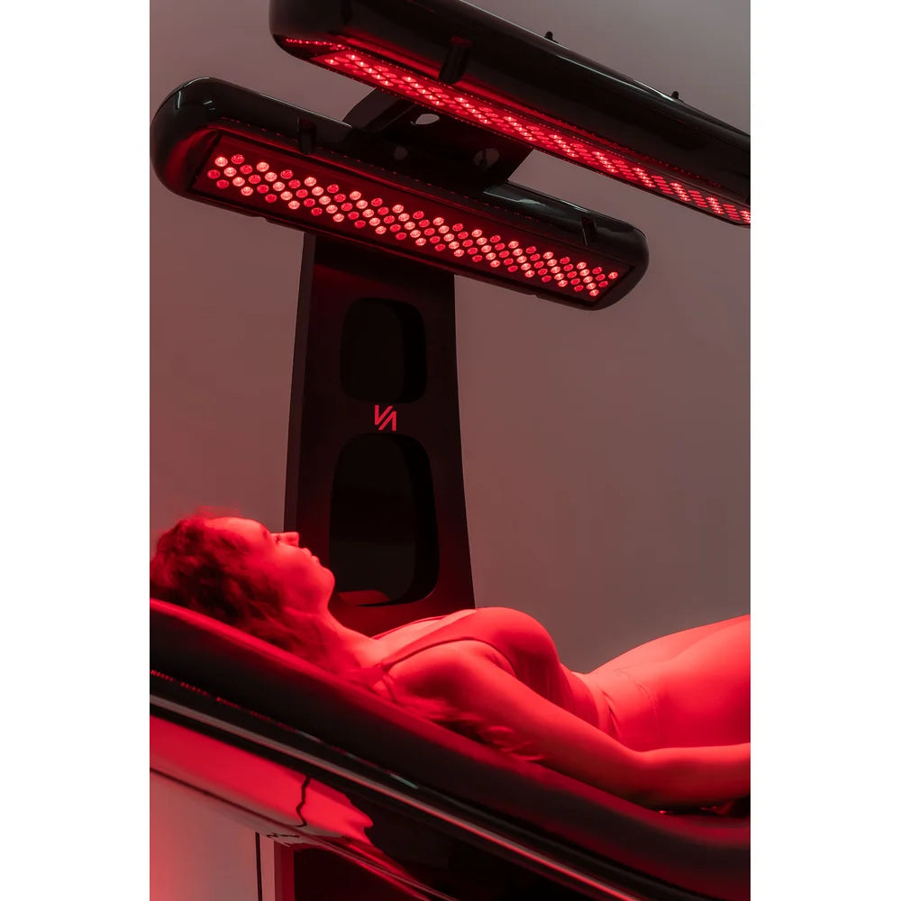 Upward view of two glowing LED lamp panels above a reclining client on the Vacu Activ Red Couch 360