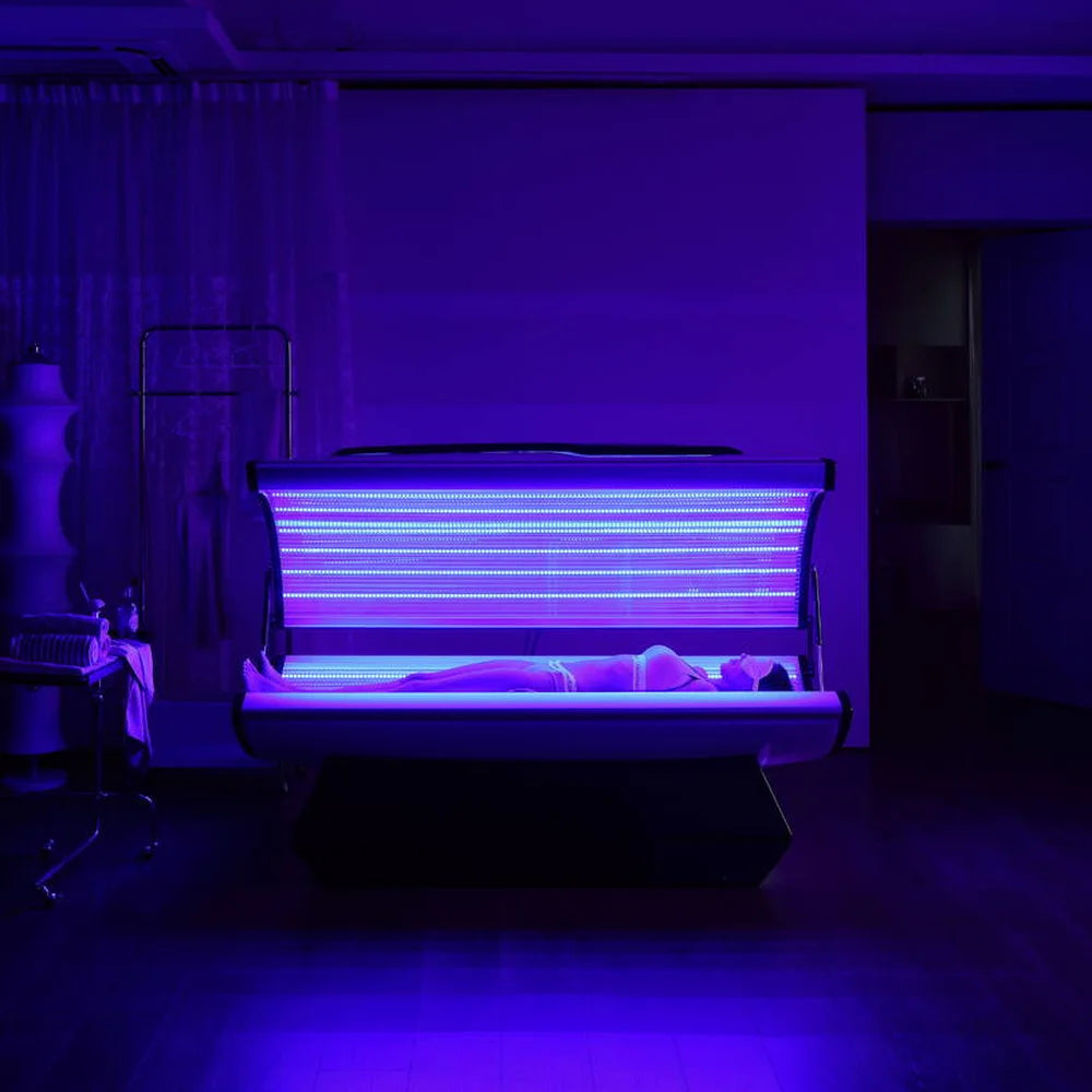 Blue 450nm LEDs illuminating a reclining person inside the open Galaxy Zero Capsule in a darkened room