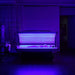 Blue 450nm LEDs illuminating a reclining person inside the open Galaxy Zero Capsule in a darkened room