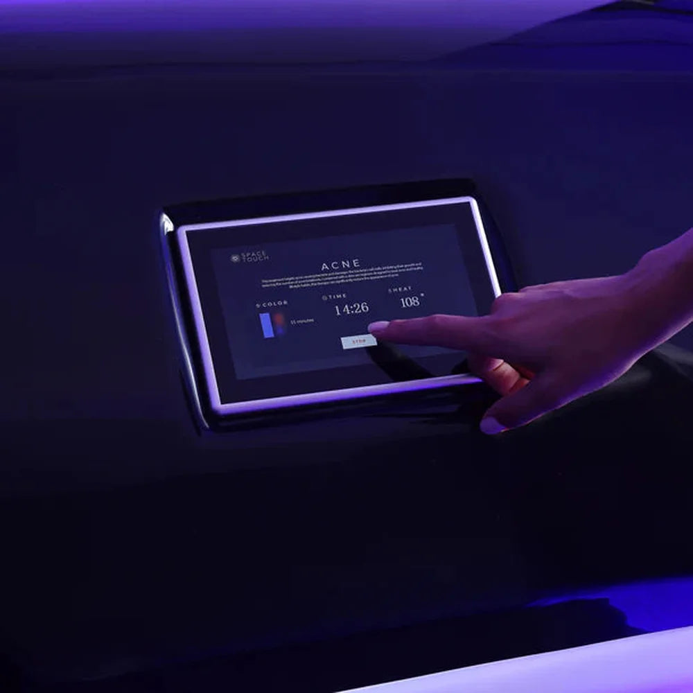 Finger selecting the acne program with timer and heat settings on the exterior touchscreen of the Spacetouch Capsule