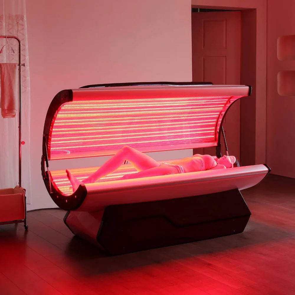 Dense rows of red LEDs above a person reclining in the Galaxy Zero Capsule Red Light Therapy unit