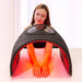 Seated woman placing her hands and forearms under the Galaxy Zero Trinty LED Device during a red light session