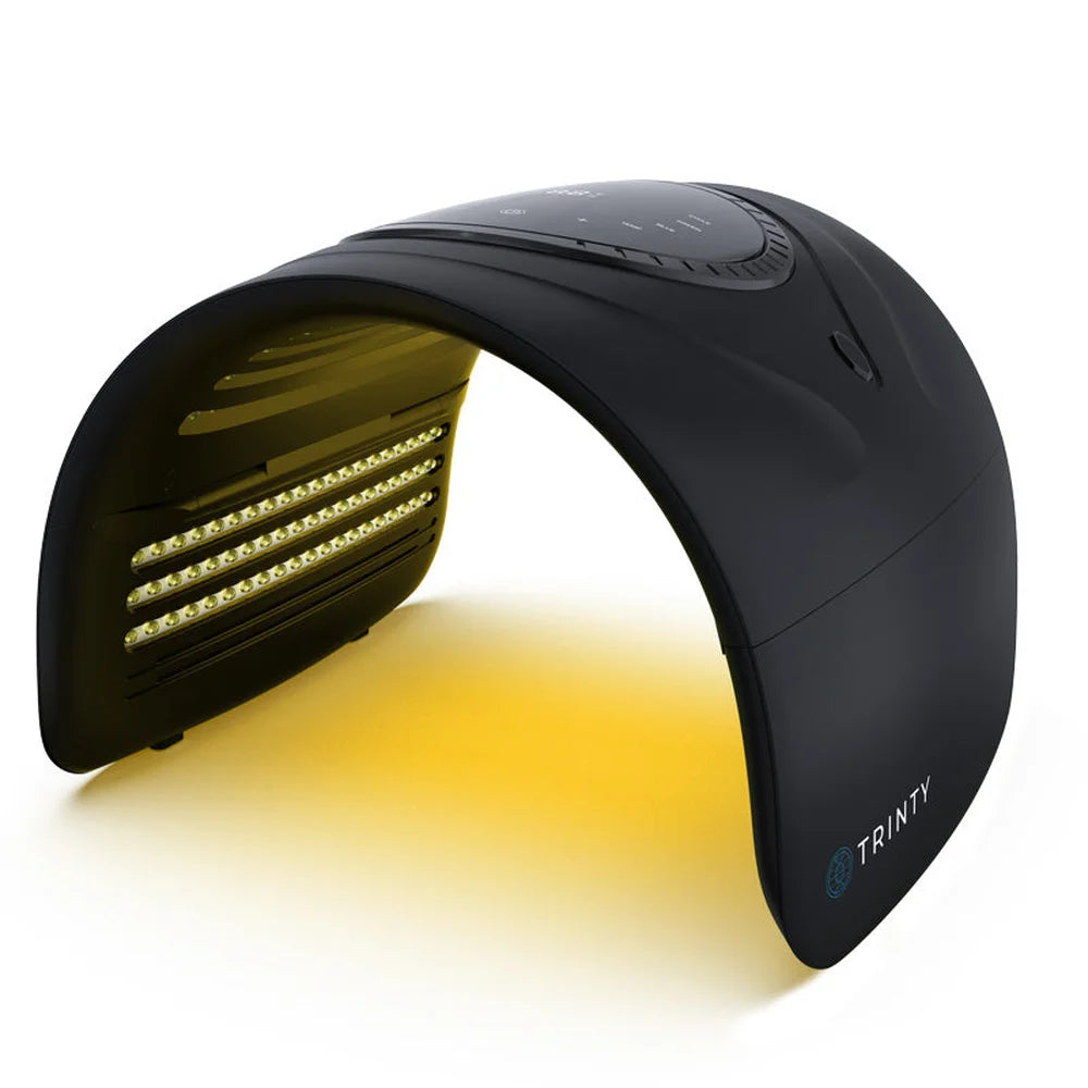 Angled studio shot of the Galaxy Zero Trinty Red Light Therapy Device glowing in yellow light mode on white