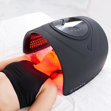 Face and shoulder session with the Galaxy Zero Trinty Red Light Therapy Device positioned over a reclining woman