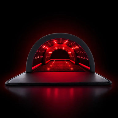 Straight-on view into the KoreLight KorePOD Full Body Light Therapy Pod with red LED rows glowing across its arched tunnel