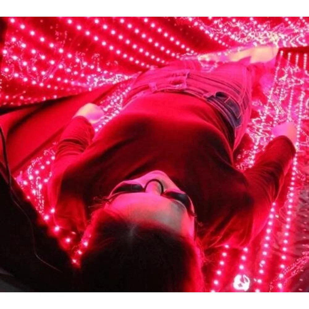Person in protective goggles lying on the lit base of the Kore KoreKapsule Full Body Red Light Therapy Device for a session