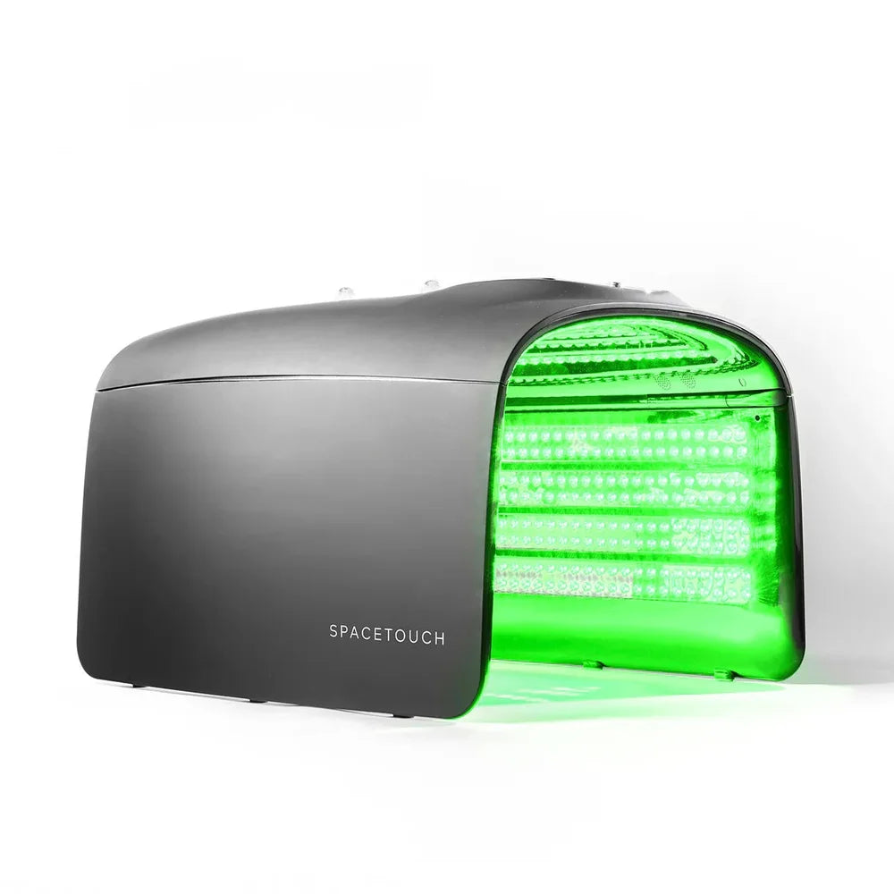 Black capsule glowing green from its LED array, the Galaxy Zero Atlas LED Therapy Device seen from a side angle