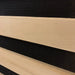 Macro of a hemlock slat edge against black carbon heater fabric in the Blisspod Bergen Sauna wall build