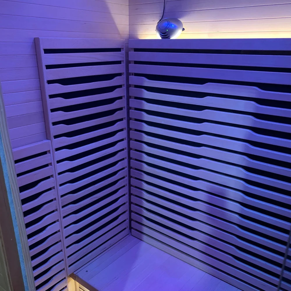 Interior of the Blisspod Helsinki Sauna Pod under purple light with backrest, heater slats and ionizer