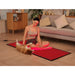 Smiling woman pets her dog while seated on the lit floor mat of the Kore KoreKapsule Red Light Therapy Chamber Kit