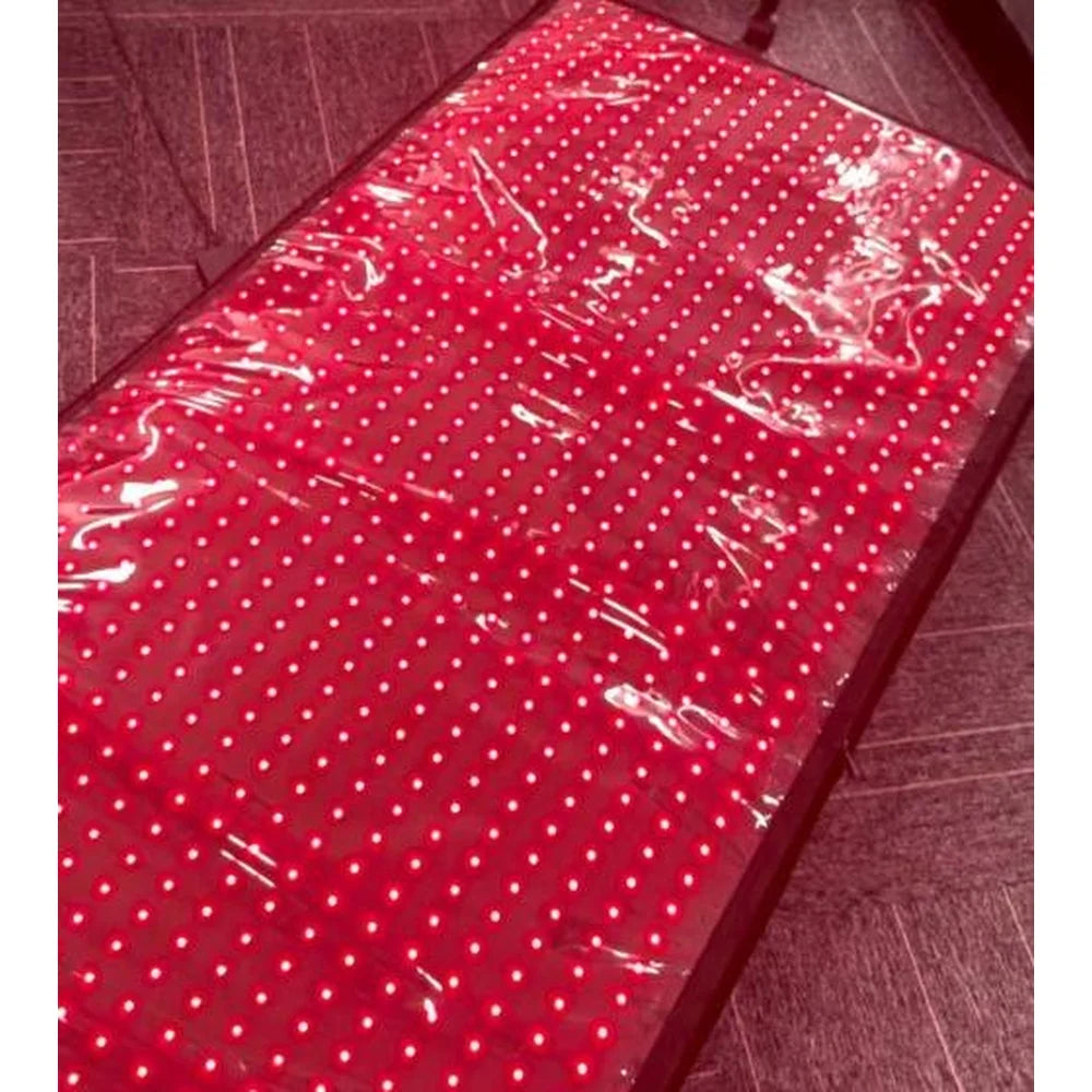 Lit panel of the Kore KoreKapsule Full Body Red Light Therapy Device laid flat on a tiled floor with an even LED grid