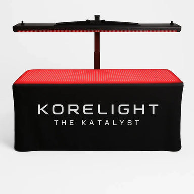 Front view of the KoreLight KoreStation Light Therapy System with overhead panel and glowing red mat table on white