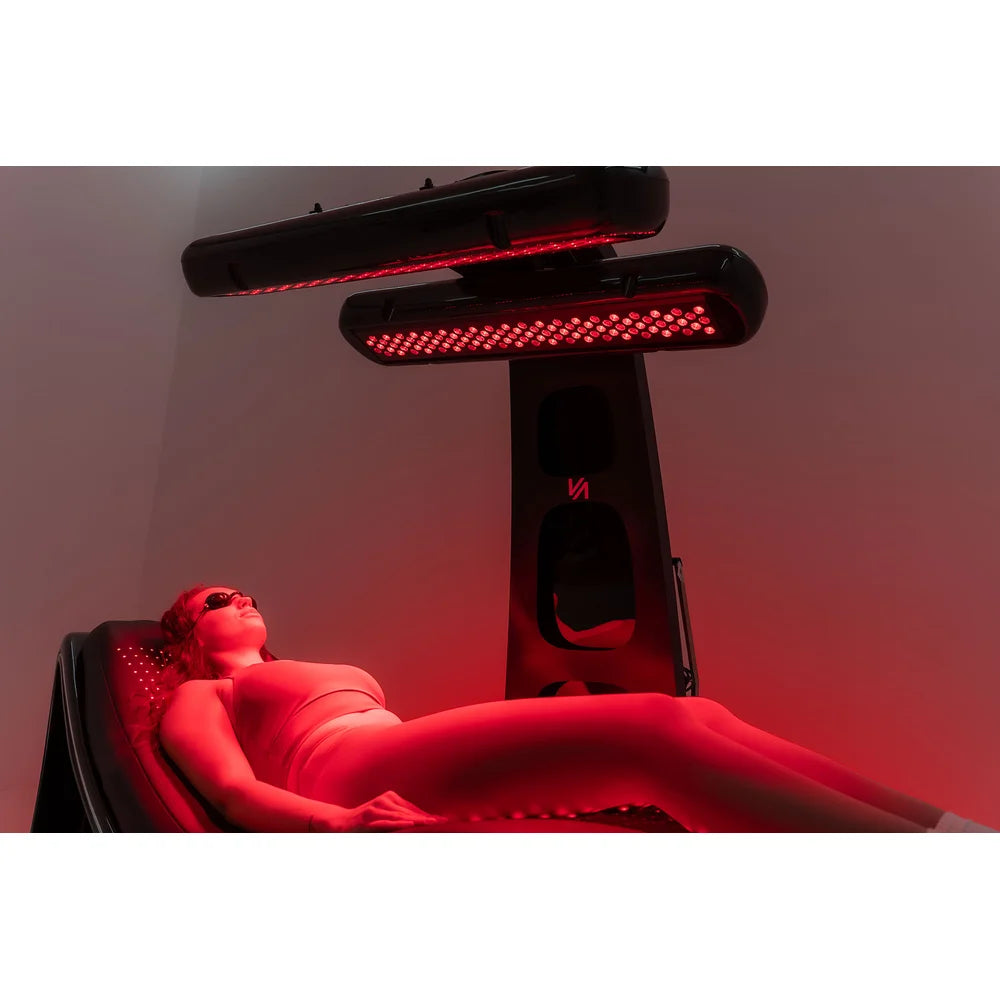 Wide low-angle studio session on the Vacu Activ Red Couch 360 with both lamp bars lit above the client