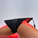 Pad wrapped and belted around a bent knee, red light escaping the edges of the Lumara Pad Infrared Therapy Pad