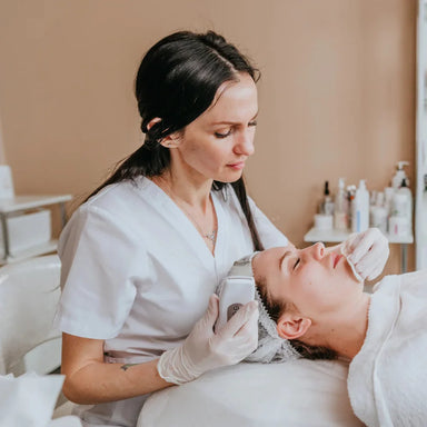 Esthetician treating a client in a med spa room of the kind served by the Lumara Systems PRO Light Therapy Panel