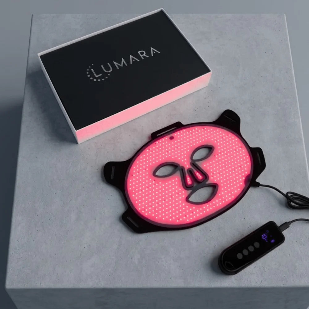 Glowing Lumara VISO LED Mask on a concrete pedestal next to its black box, cable and handheld controller