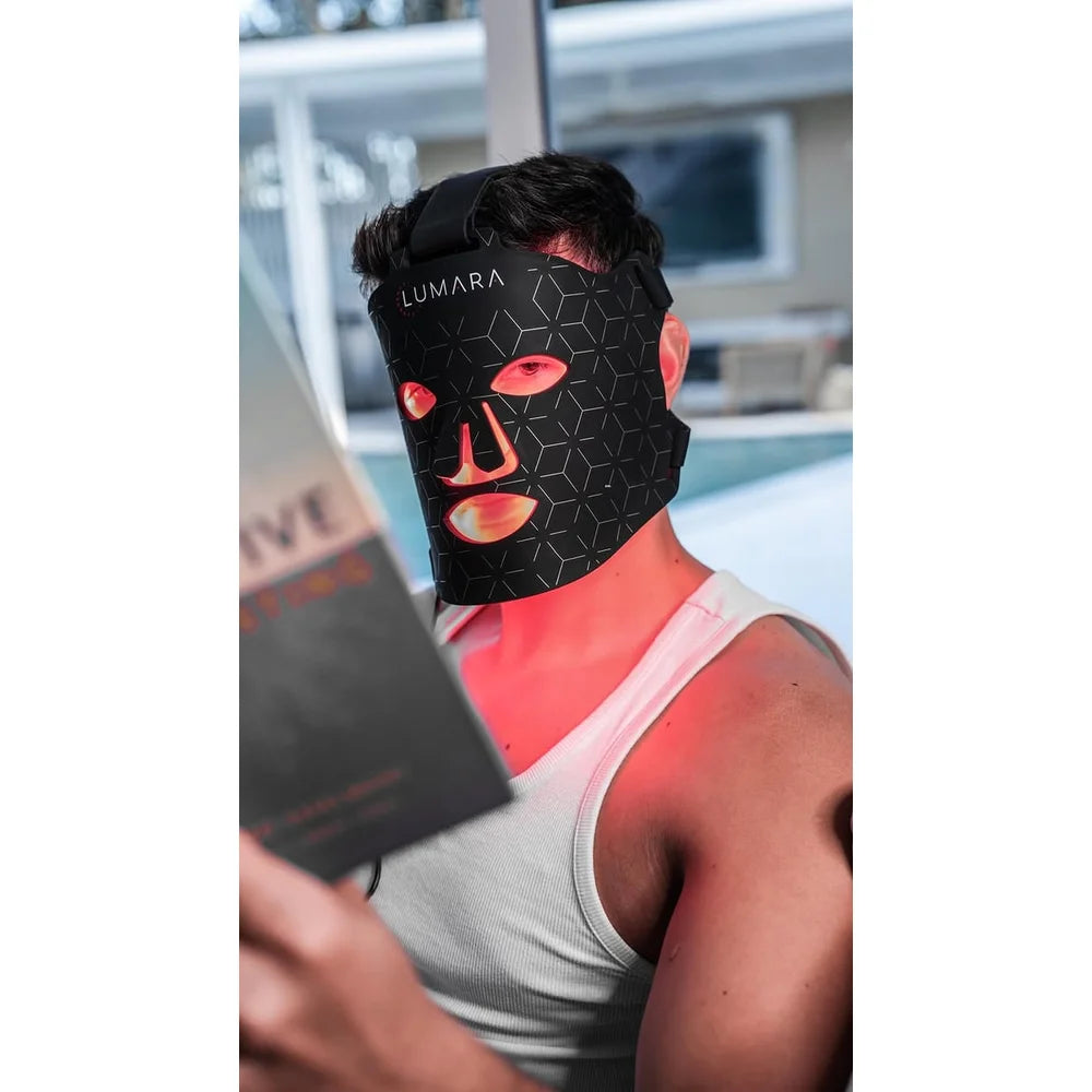 Man reading poolside while wearing the Lumara VISO with red light glowing at the cutouts