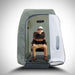Smiling older man sitting on a wooden chair inside the Oxyrevo Heal 40 Oxygen Chamber with the door open