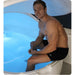 Man seated on the edge of an open Dreampod V2 Isolation Tank with blue interior lighting on the salt water