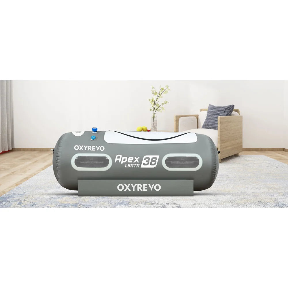 Grey OxyRevo Apex36 Hyperbaric Chamber set up on a rug in a bright living room beside an armchair