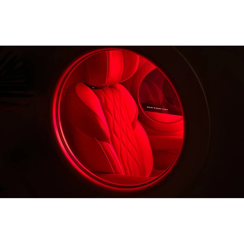Round window view of quilted leather seating lit by red light inside the OxyRevo Space60 Hyperbaric Chamber