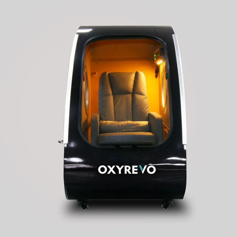 Front facing black OxyRevo Space60 Oxygen Therapy Chamber with open door and seat in the lit cabin