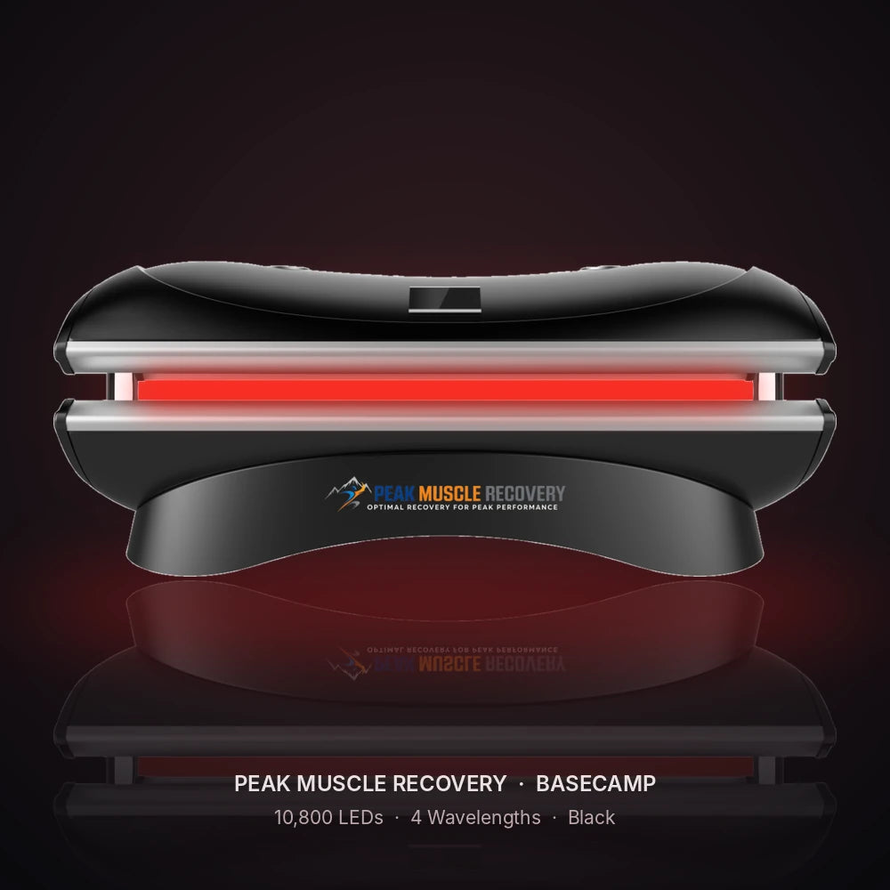 Black Peak Muscle Recovery Basecamp Red Light Therapy Bed with red LEDs glowing in a dark studio