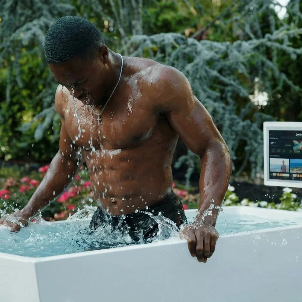 Man splashing in the Primal Plunges Blizzard cold plunge in a backyard