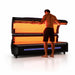 Man lifting the illuminated upper canopy of the RevitalCore Apex M6 Red Light Bed with orange LED panels lit