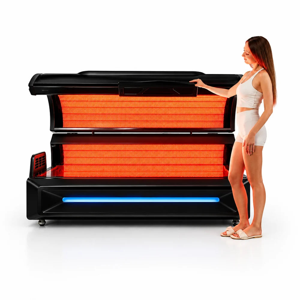 Woman in white activewear beside the open Apex M6 Full-Body Light Bed with both dense LED arrays glowing