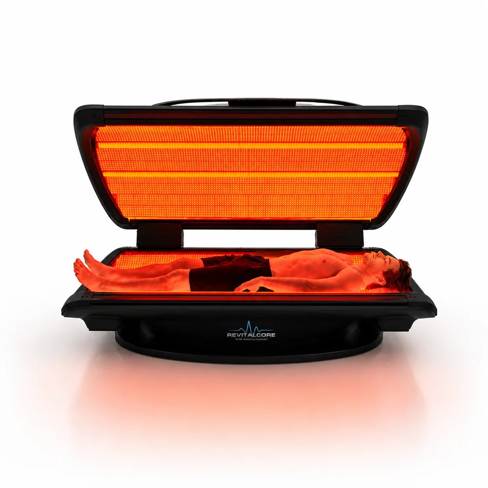 Man lying full length under the red glowing canopy array of the RevitalCore Elevate M7 Light Bed during a session