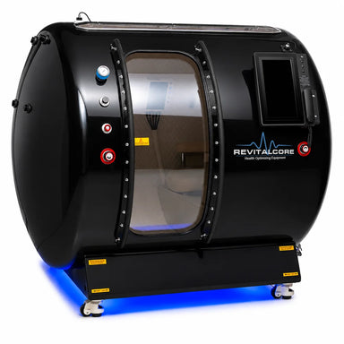 Angled studio shot of the RevitalCore Summit Walk-In Hyperbaric Chamber with clear sliding door, LCD console and lit base