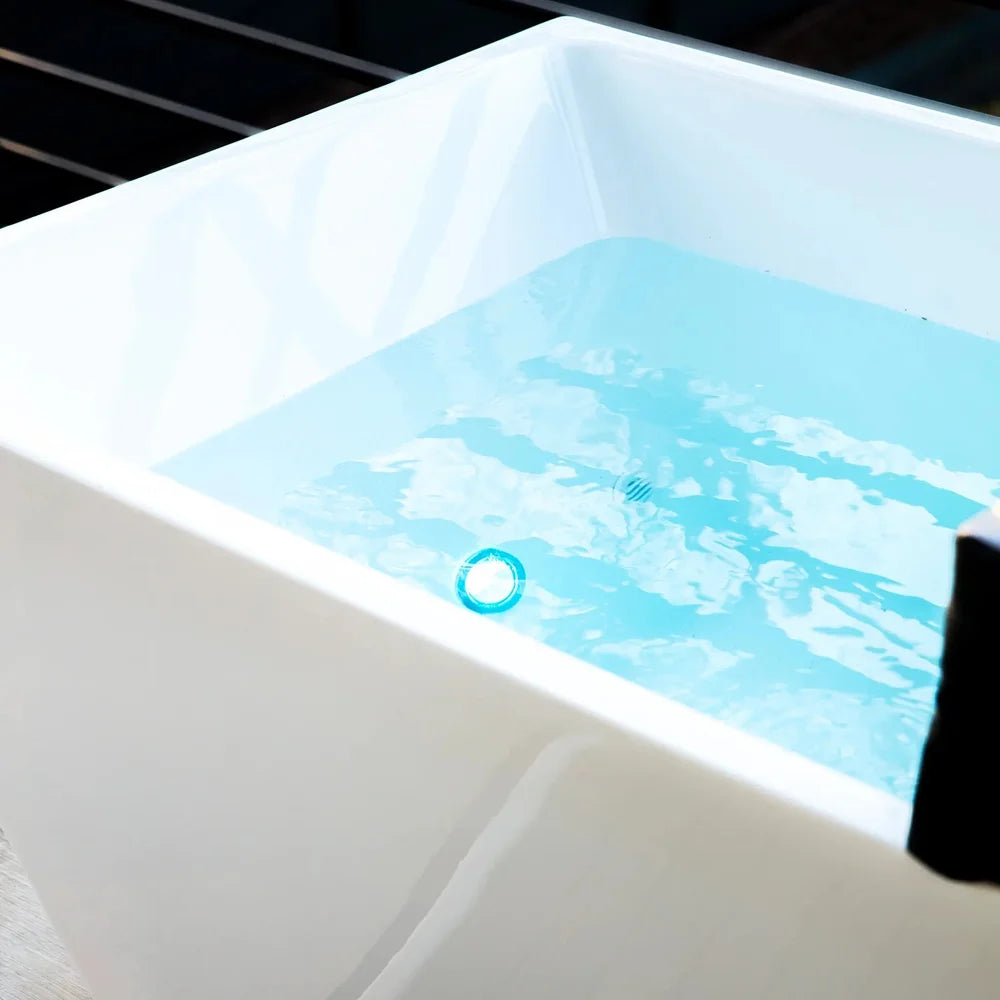 Close-up of the color changing LED light glowing blue under the water in the Revive Plunge Acrylic Plunge Tub