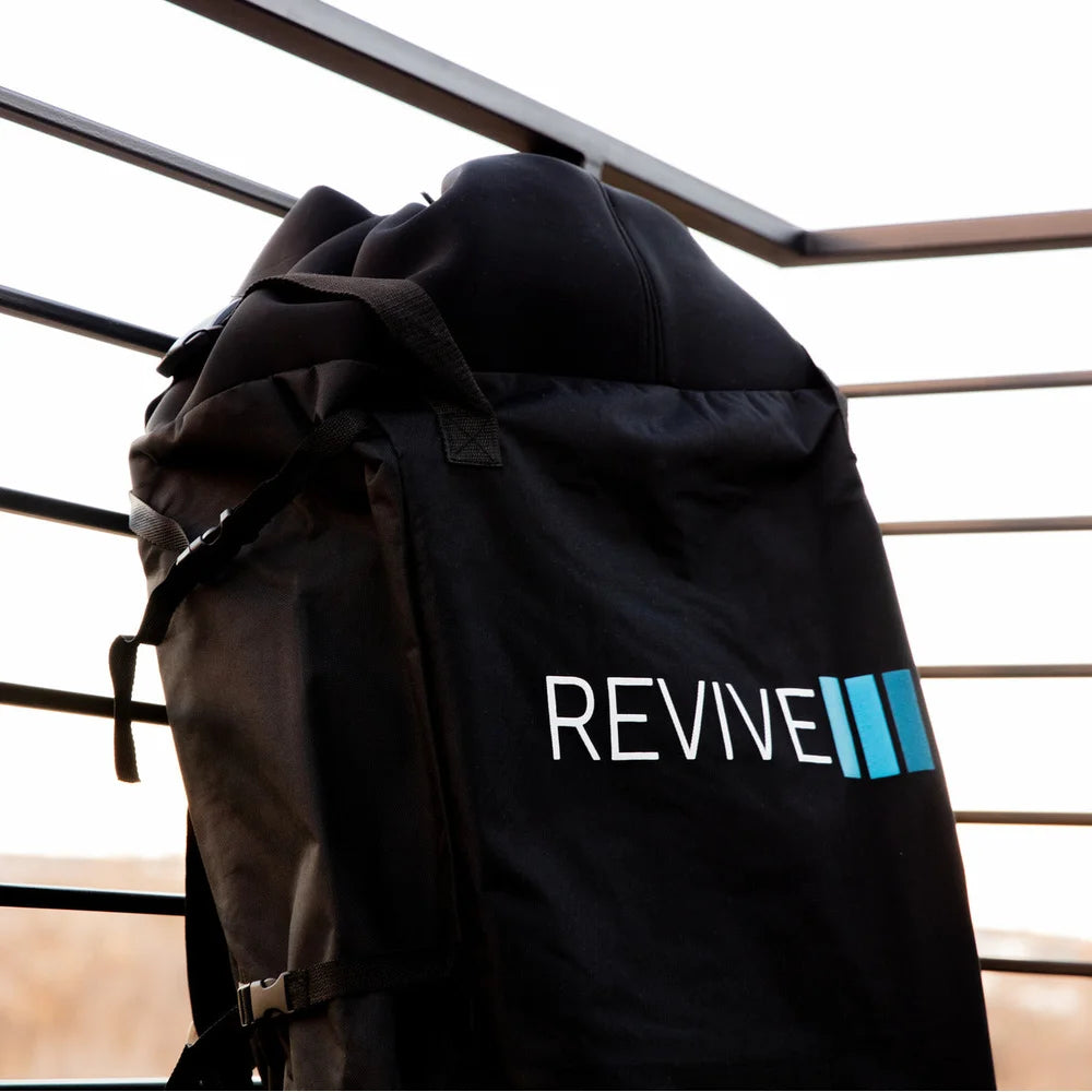 Black storage backpack for the Revive Inflatable Pod Plunge Portable Cold Plunge hanging on a metal railing outdoors